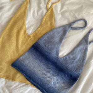 May include: Two knitted halter tops. One is a solid yellow, the other is blue with a gradient effect. Both tops have a deep V-neck and thin straps. The tops are displayed on a white surface.