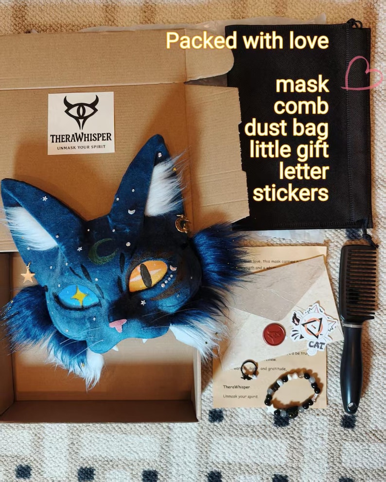 May include: A blue cat-shaped mask with white fur accents, a crescent moon, and star details. The set includes a black dust bag with text, a black comb, a letter in an envelope with a wax seal, stickers, a small ring, and a beaded bracelet.