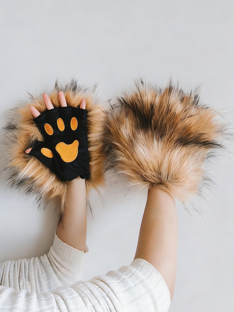 May include: Novelty gloves with a black palm and orange paw print design, surrounded by long, brown and black faux fur. The gloves are designed to resemble animal paws, perfect for costumes or fun.