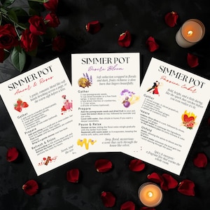 Peut inclure: Trois cartes de recettes pour pots à mijoter, entourées de pétales de roses rouges et de bougies allumées. Les cartes présentent des instructions pour "Amour & Roses", "Desire Bloom" et "Passion Ember", avec des illustrations.