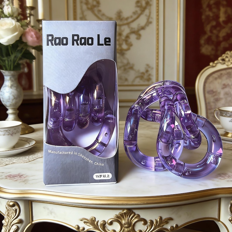 Op de afbeelding: Een paars Rao Rao Le puzzelspeelgoed, met een doos met de tekst "Rao Rao Le" en "Vervaardigd in Shenzhen, China". De puzzel is een reeks in elkaar grijpende ringen. De doos toont de puzzel in de vorm van een hand.