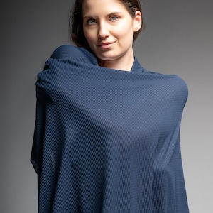 May include: A woman draped in a navy blue, textured fabric. The fabric appears to be a shawl or wrap, with a subtle ribbed pattern. A roll of the same fabric is visible in the lower right corner, suggesting it's sold by the yard.