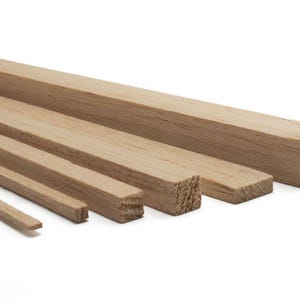 May include: A collection of unfinished wooden dowels of varying sizes, ranging from thin strips to thicker square pieces. The wood has a natural, light brown color and visible grain.