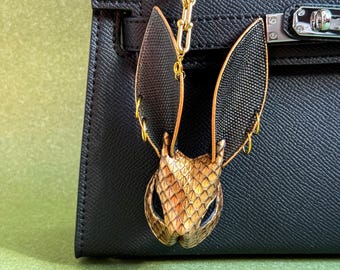 Chaveiro de couro artesanal em formato de coelho com estampa de pele de cobra dourada.