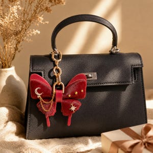This Burgundy Gothic Vintage Leather Butterfly Bag Charm is a handmade purse charm and handbag charm, crafted from horsehair and lambskin, with gold chain, moon, and star details, also works as a keychain or car mirror pendant.
