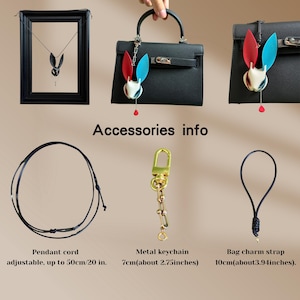 Op de afbeelding: Een zwart omrande hangerketting met een konijnontwerp en een zwarte handtas met een konijnvormige bedel. Accessoires info: Verstelbaar koord tot 50cm, metalen sleutelhanger 7cm en tasbedelriem 10cm.