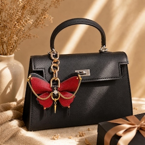 This Burgundy Gothic Vintage Leather Butterfly Bag Charm is a handmade purse charm and handbag charm, crafted from horsehair and lambskin, with gold chain, moon, and star details, also works as a keychain or car mirror pendant.