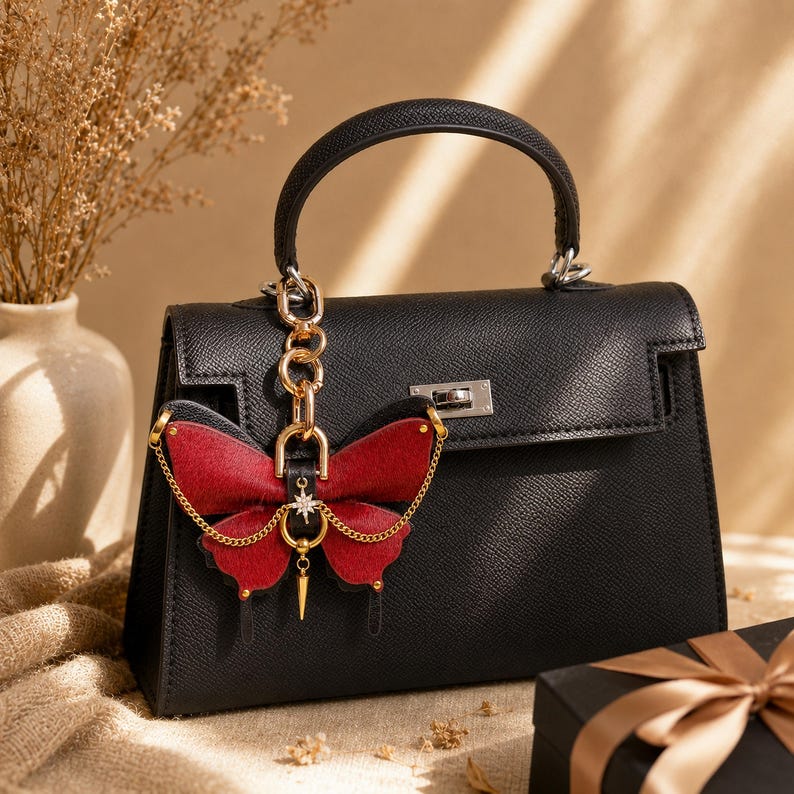 This Burgundy Gothic Vintage Leather Butterfly Bag Charm is a handmade purse charm and handbag charm, crafted from horsehair and lambskin, with gold chain, moon, and star details, also works as a keychain or car mirror pendant.