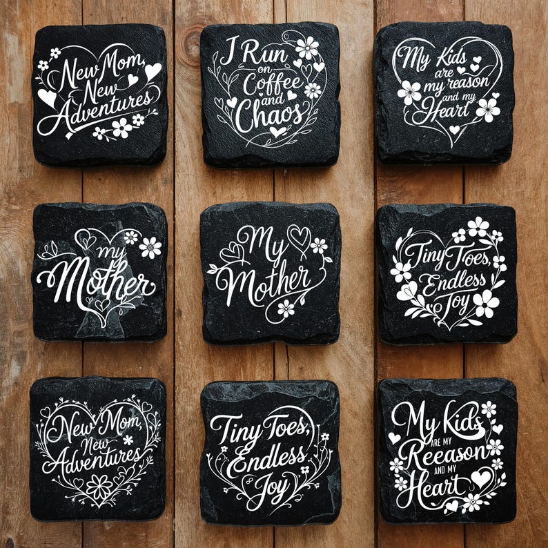 Peut inclure: Un ensemble de neuf dessous de verre carr&eacute;s en ardoise noire avec des textes blancs imprim&eacute;s et des motifs de c&oelig;urs floraux. Les phrases incluent New Mom New Adventures, I Run on Coffee and Chaos, My Kids are my reason and my Heart, My Mother et Tiny Toes Endless Joy.