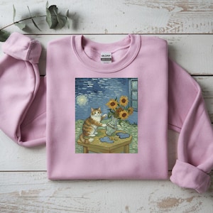 Könnte beinhalten: Hellrosa Sweatshirt mit Grafikdruck. Die Grafik zeigt eine Katze und Sonnenblumen in einer Vase, im Stil der Gemälde von Van Gogh. Die Katze ist orange und weiß. Der Hintergrund zeigt eine sternenklare Nacht.