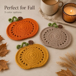 Pode incluir: Três bases para copos em crochê com formato de abóbora nas cores laranja, bege e amarelo, cada uma com um caule marrom e uma gavinhas verde. O texto "Perfect for Fall" e "3 color options" é visível acima das bases na superfície.