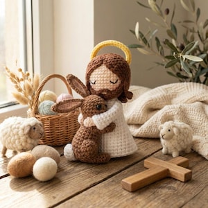 May include: A collection of handmade crochet items, including a figure of Jesus embracing a brown bunny, a small white sheep, a wooden cross, and a basket with yarn eggs. The items are arranged on a wooden surface, creating a warm and inviting scene.