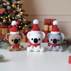 Può includere: Tre ornamenti di koala all'uncinetto fatti a mano. Ogni koala indossa un cappello da Babbo Natale rosso e bianco e una sciarpa rossa. I koala sono in tonalità di marrone, bianco e grigio, con nasi e occhi neri. Decorazioni natalizie.