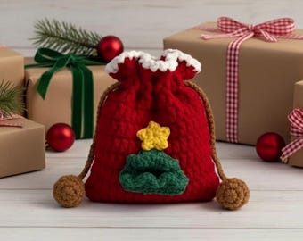 Puede incluir: Una bolsa de regalo navideña roja tejida a ganchillo con una parte superior con volantes blancos, un cordón marrón y una aplicación de árbol de Navidad verde y amarillo. Pompones marrones están unidos a los extremos del cordón. Cajas de regalo y adornos en el fondo.