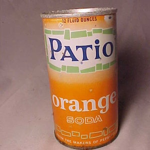 May include: Vintage Patio Orange Soda can. The can is orange with white and green accents. The text "Patio" is in blue, and "orange soda" is in white. It reads "12 fluid ounces" at the top. The can is from the makers of Pepsi-Cola.