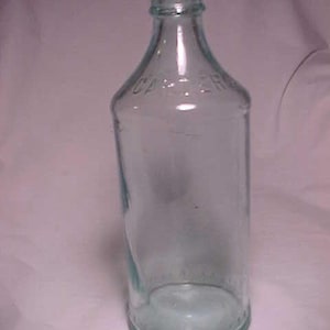 May include: A clear glass bottle with a rounded bottom and a slightly flared neck. The bottle has a textured surface and the word "CARTER" is embossed on the front.
