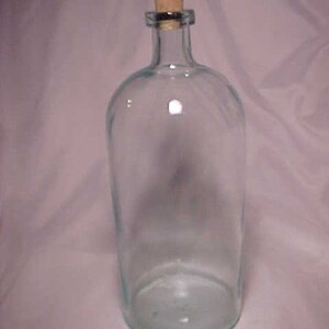 May include: A clear glass bottle with a cork stopper. The bottle is tall and cylindrical with a rounded bottom.