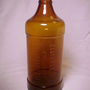 May include: A brown glass bottle with a label that reads "Sanford's  Inks One Quart And Library Paste".