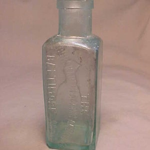 May include: A clear glass bottle with a textured surface. The bottle has a label that reads "Dr. J.H. McLean's" and "The Great" in a cursive font.