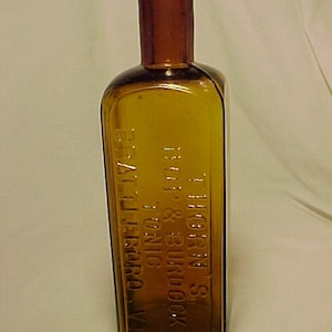 May include: A brown glass bottle with a square body and a round neck. The bottle is labeled "T. HORN, S. & SURG.  DR.  TONIC  EST. 1871  JEFFERSON - VA."
