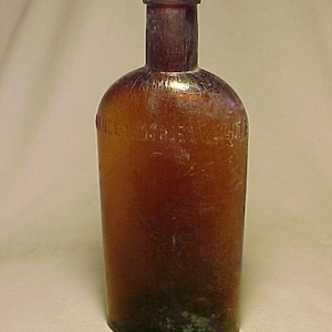 May include: A vintage amber glass bottle with a rounded body and a narrow neck. The bottle has a slightly frosted appearance and is embossed with the text "INCE & HOPPER, BOSTON".