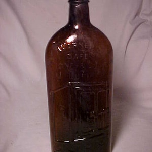 May include: A brown glass bottle with a label that reads "Dr. Yen's Safe & Sure Eye Water". The bottle has a rounded bottom and a narrow neck.