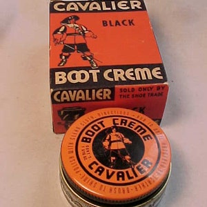 May include: A vintage tin of Cavalier Boot Creme shoe polish in black. The tin is orange with black lettering and a cartoon image of a cavalier wearing a plumed hat and holding a sword. The text on the tin reads "Cavalier Boot Creme" and "Sold Only By The Shoe Trade".
