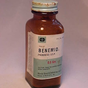 May include: A brown glass bottle with a blue lid labeled "TABLET BENEMID (PROBENECID) U.S.P. 0.5 Gm.". The label also includes the text "CAUTION: Federal law prohibits dispensing without prescription. Merck Sharp & Dohme, West Point, Pa. Division of Merck & Co., Inc."