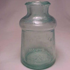 May include: A clear glass bottle with a rounded body and a narrow neck. The bottle has a textured surface and the words "WORCESTER" and "CO" are embossed on the bottom.