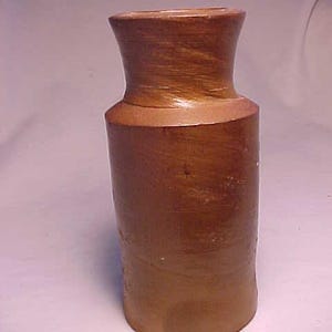May include: A brown stoneware pottery jar with a wide mouth and a rounded body. The jar has a smooth, slightly textured surface.
