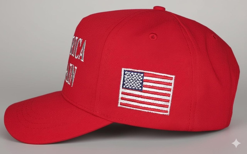 May include: A red baseball cap with the words "AMERICA AGAIN" embroidered in white. An American flag patch is on the side. The cap has a curved brim and a button on top.