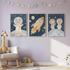 Könnte beinhalten: Drei gerahmte Kunstdrucke mit Weltraum-Illustrationen. Einer zeigt einen Bären-Astronauten mit einem Teleskop auf einem Mond. Ein anderer zeigt eine Rakete. Der dritte zeigt ein Löwen- und Giraffen-Astronauten-Duo auf einem Mond, alles vor einem Sternenhimmel.