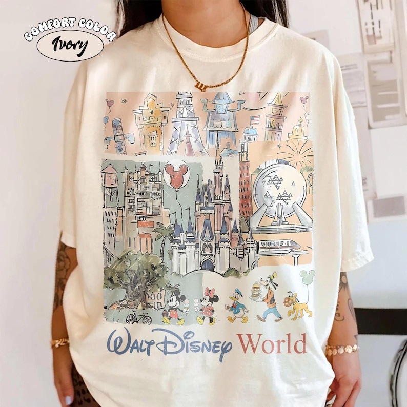 Peut inclure: T-shirt ivoire Comfort Color avec une illustration color&eacute;e des monuments et personnages de Walt Disney World. Le design comprend le ch&acirc;teau de Cendrillon, Spaceship Earth et Mickey et Minnie Mouse. Les mots "Walt Disney World" sont imprim&eacute;s en bas.
