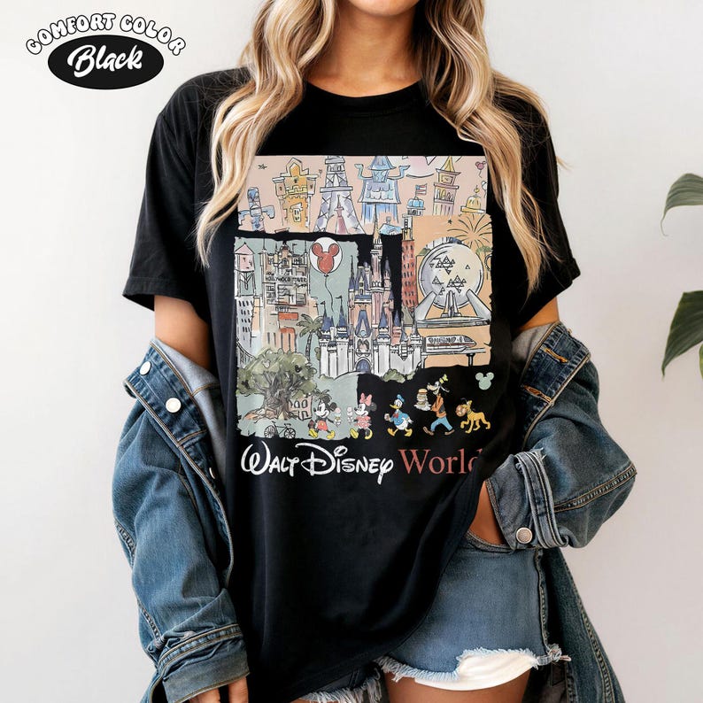 Peut inclure: T-shirt noir Comfort Colors avec un graphisme color&eacute; des monuments et personnages de Walt Disney World. Le design comprend le ch&acirc;teau de Cendrillon, Mickey Mouse et d'autres &eacute;l&eacute;ments embl&eacute;matiques. Le texte "Walt Disney World" est imprim&eacute; en dessous.
