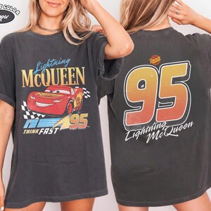Puede incluir: Camiseta gris oscuro con Lightning McQueen de la pel&iacute;cula Cars. El gr&aacute;fico frontal muestra a McQueen con el n&uacute;mero 95 y "Think Fast". La parte trasera muestra un gran "95" y "Lightning McQueen".