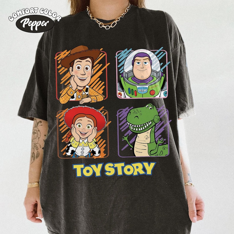 May include: Dark gray t-shirt featuring four cartoon character portraits from the movie "Toy Story": Woody, Buzz Lightyear, Jessie, and Rex. The words "Toy Story" are printed in large, yellow letters below the characters.