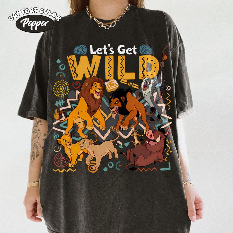 May include: Dark gray t-shirt featuring a colorful graphic of characters from The Lion King. The design includes the text "Let's Get WILD" in yellow and orange, with images of Simba, Scar, Timon, Pumbaa, and other characters.