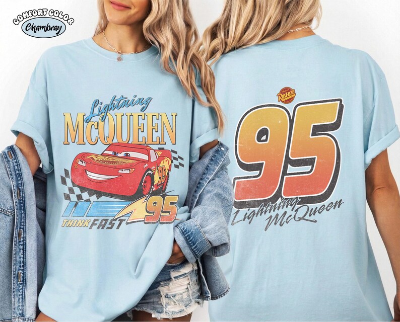 Puede incluir: Camiseta azul claro con Lightning McQueen de la pel&iacute;cula Cars. El frente muestra el personaje, el texto "Lightning McQueen" y "95". La parte trasera presenta un gran "95" y el texto "Lightning McQueen".