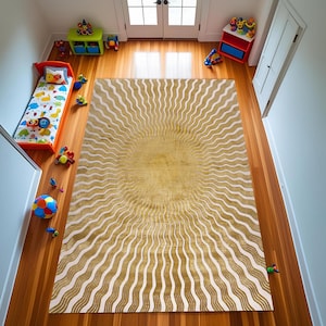 Könnte beinhalten: Ein großer, goldener Teppich mit einem Sonnenstrahl-Design auf einem Holzboden. Die Mitte des Teppichs ist goldfarben, mit strahlenden weißen und goldenen wellenförmigen Linien. Der Raum zeigt auch ein Kinderbett, Spielzeug und Aufbewahrungsmöbel.