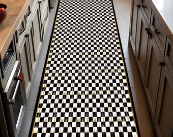 May include: A long, rectangular kitchen runner rug with a black and white checkered pattern. The rug has a black border with a thin gold accent. The rug is placed between two kitchen cabinets.