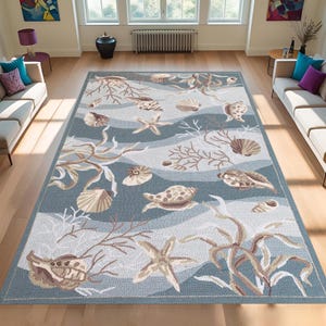 Puede incluir: Una alfombra rectangular con temática costera. La alfombra presenta un fondo azul con rayas onduladas e ilustraciones de conchas marinas, estrellas de mar y corales en tonos beige y marrón. La alfombra está diseñada para una sala de estar.