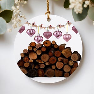 Peut inclure: Ornement de Noël rond avec un design festif. Il présente une guirlande de teckels portant des bonnets de Père Noël, ainsi que des ornements roses en forme de cœur. Une pile de bûches forme la base, créant un thème de vacances rustique.