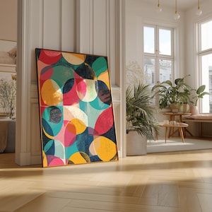 Può includere: Una stampa artistica incorniciata con forme colorate sovrapposte in tonalità di rosso, rosa, giallo, verde acqua e blu navy. L'opera d'arte è appoggiata a una parete bianca in una stanza luminosa con pavimento in legno.