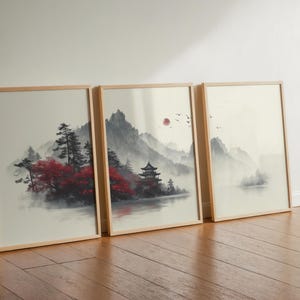 Puede incluir: Tres impresiones artísticas enmarcadas que representan un sereno paisaje asiático. La obra de arte muestra montañas, árboles y un lago en tonos apagados, con toques de rojo. Las impresiones están en marcos de madera clara.