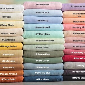 K&ouml;nnte beinhalten: Eine Sammlung gefalteter Musselin-Stoffmuster, gestapelt in drei Spalten, mit verschiedenen Farben, die mit Text beschriftet sind, darunter Cloud White, Linen Rose, Lavender Haze, Cream, Pastel Blue, Strawberry Ice, Baby Chick, Blue Sky, Blush Pink.