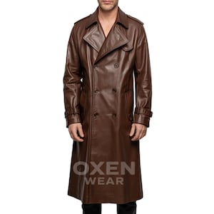 Könnte beinhalten: Ein brauner Ledertrenchcoat mit doppelreihigem Design. Der Mantel hat einen Reverskragen, Schulterklappen und ein Gürteldetail an den Ärmeln. Der Mantel ist knielang und trägt unten den Text "OXEN WEAR".