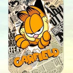 Op de afbeelding: Rechthoekige telefoonhoes met Garfield, de oranje cartoonkat, die door een achtergrond van krantenknipsels breekt. Het woord "GARFIELD" staat in oranje letters. Bovenop zit een zwarte lus.