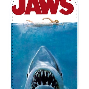 Könnte beinhalten: Eine weiße, rechteckige Handyhülle mit dem Filmplakat von "Jaws". Das Poster zeigt einen Hai mit offenem Maul unter einem Schwimmer im Wasser. Das Wort "JAWS" steht in großen roten Buchstaben oben.