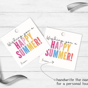 May include: Two square white gift tags with a hole punch at the top. The text reads Wishing you a HAPPY SUMMER! in pink, yellow, and blue letters. Below the text, the word From is printed with a line for a name. A grey ribbon is visible.