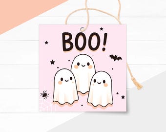 Può includere: Un'etichetta quadrata rosa a tema Halloween con la scritta "BOO!" in grandi lettere nere. Sotto il testo sono raffigurati tre fantasmi dei cartoni animati con facce sorridenti, insieme a stelle, un ragno e un pipistrello.